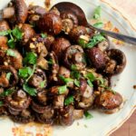 roasted mushrooms on a plate with a serving spoon