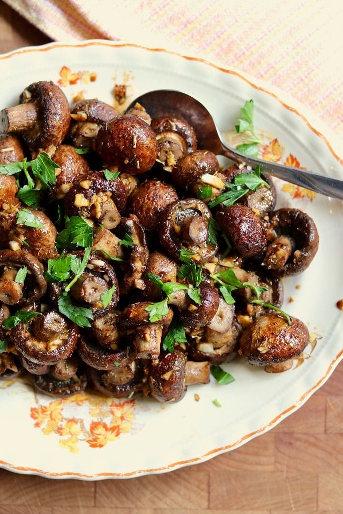 roasted mushrooms on a plate with a serving spoon
