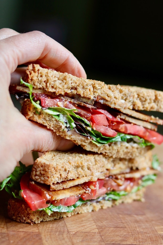 vegan blt sandwich made with tofu bacon sliced in half and stacked