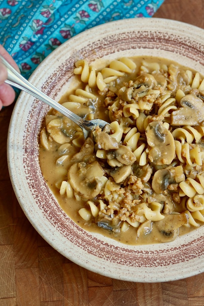 mushroom stroganoff being picked up with a fork over a plate
