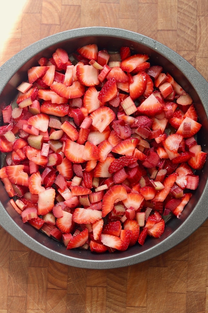 strawberries rhubarb added on top of butter sugar mixture in cake pan