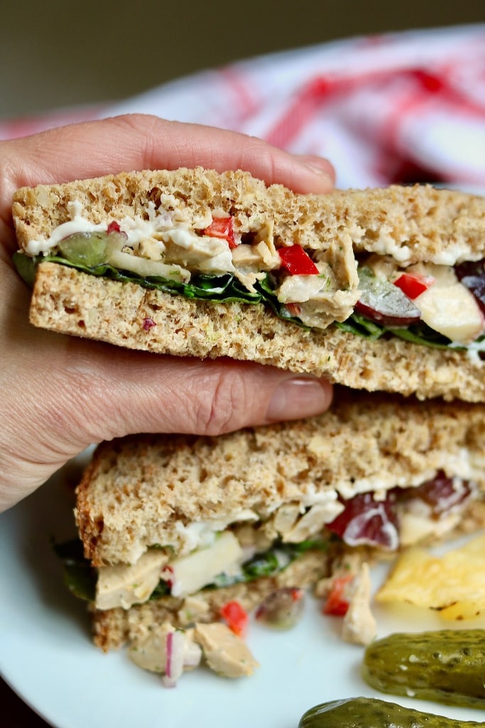 half a vegan chicken salad sandwich being held 