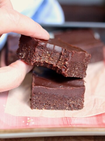 raw vegan brownie with a bite missing being picked up