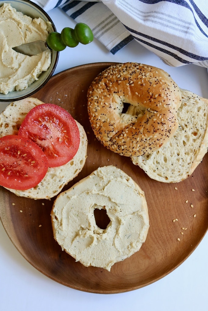 bagels with vegan cream cheese and tomatoes on a wooden platter