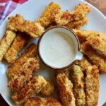 vegan zucchini fries on a white plate with ranch dressing