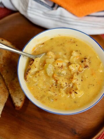 a bowl of cauliflower soup served with a slice of bread