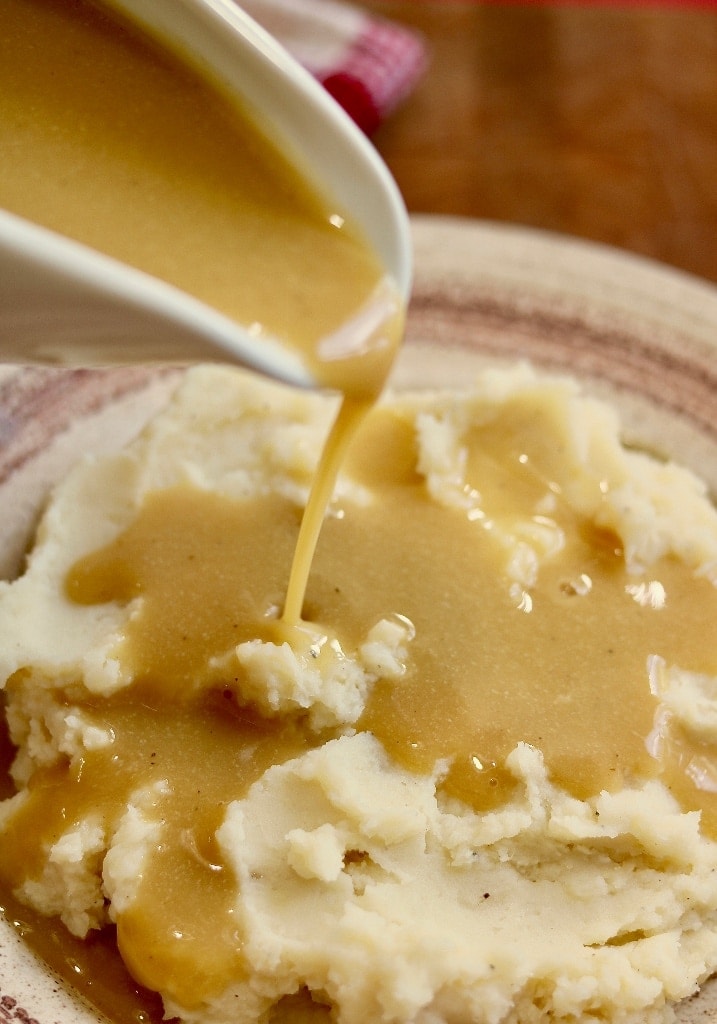 vegan gravy being poured over a plate of mashed potatoes