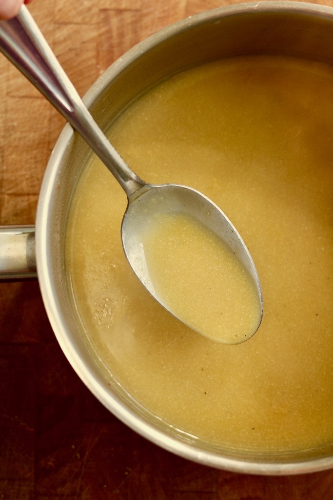 a spoonful of gravy being taken from a gravy pot