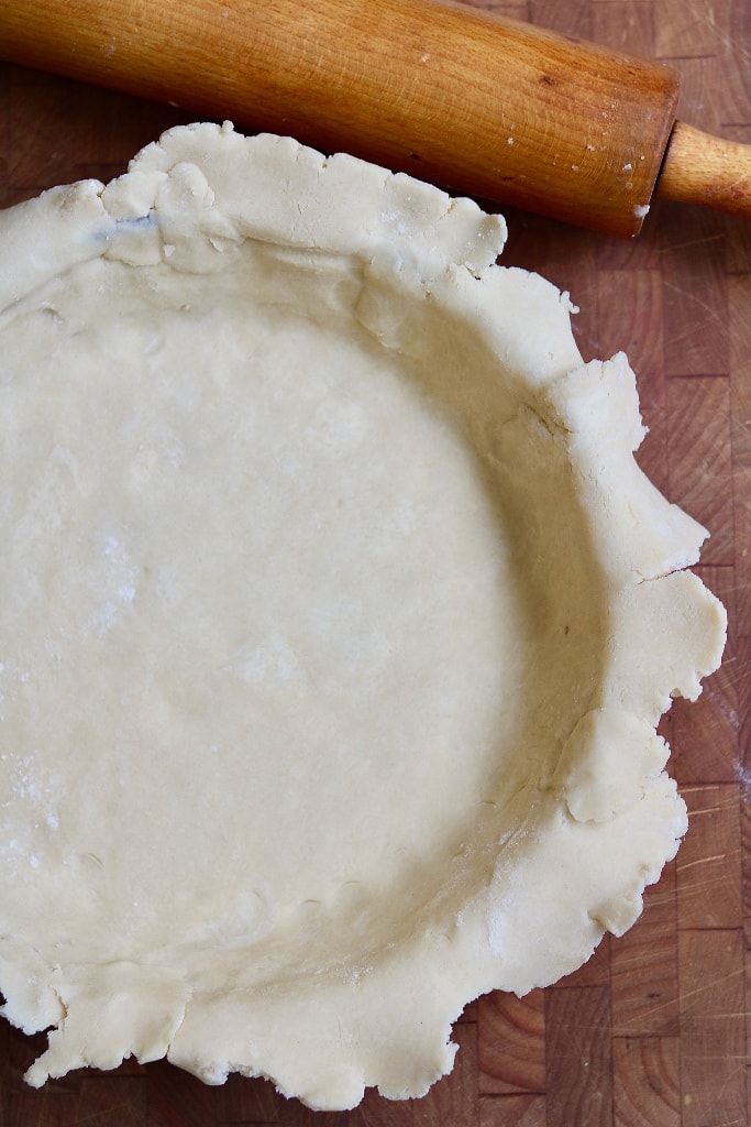 dough being fitted into glass pie plate