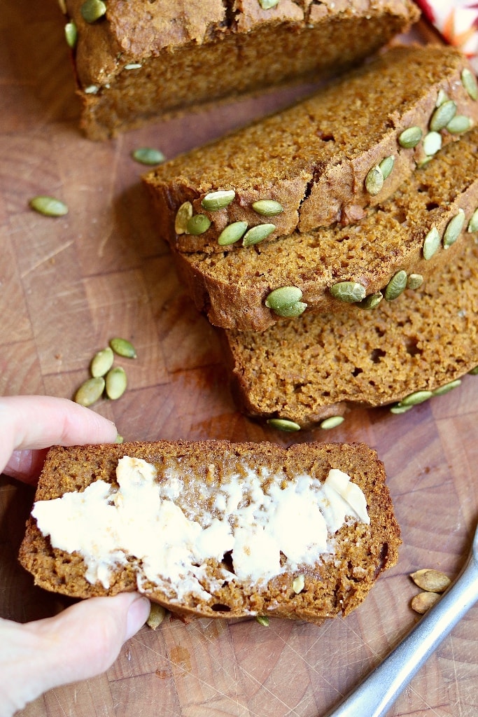 a slice of buttered pumpkin bread on a cutting board