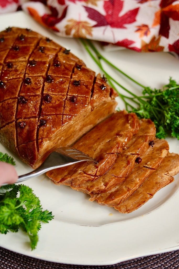 vegan ham slices on a platter with a fork