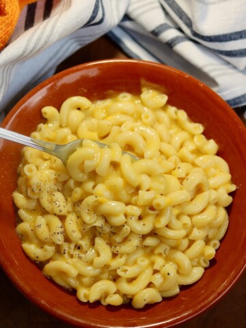 vegan mac and cheese in a brown bowl with a fork