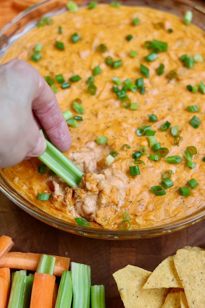 celery stick being dipped into buffalo dip