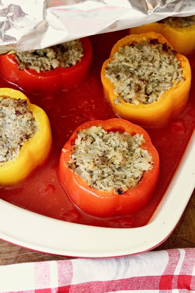 stuffed peppers in a baking dish with tomato sauce