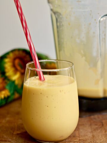 mango smoothie in a glass with a straw