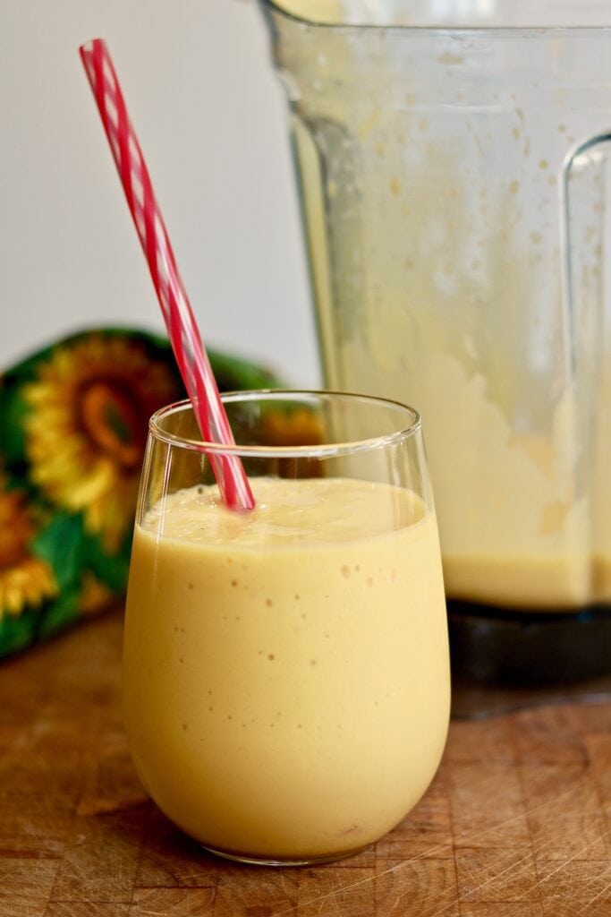 mango smoothie in a glass with a straw