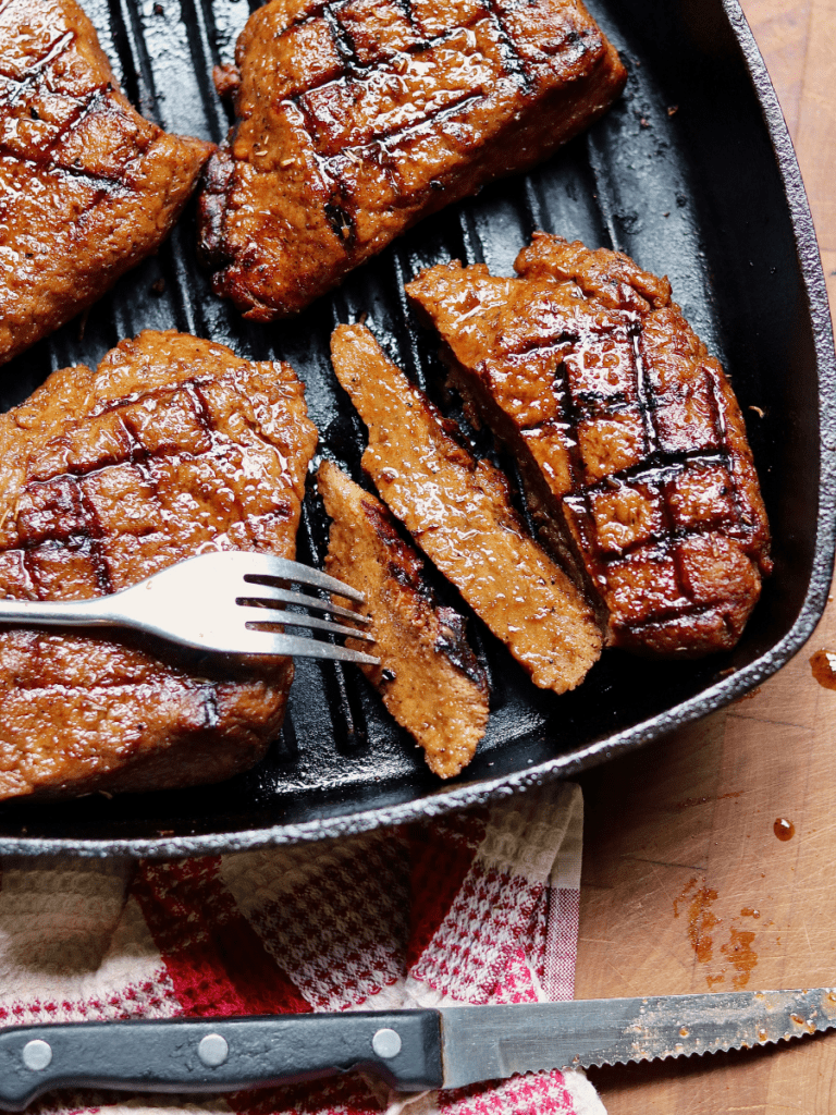 vegan steak in a grill pan being sliced