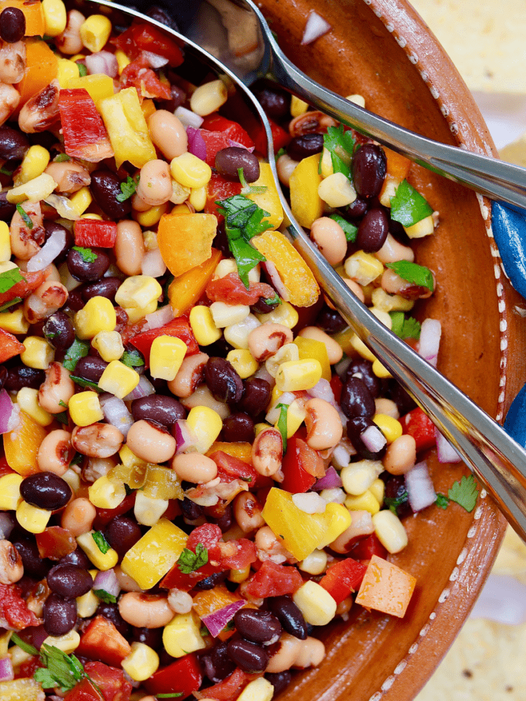 cowboy caviar mixed together in salad bowl with serving spoons