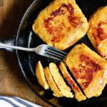 three vegan chicken pieces cooked in a frying pan partially sliced