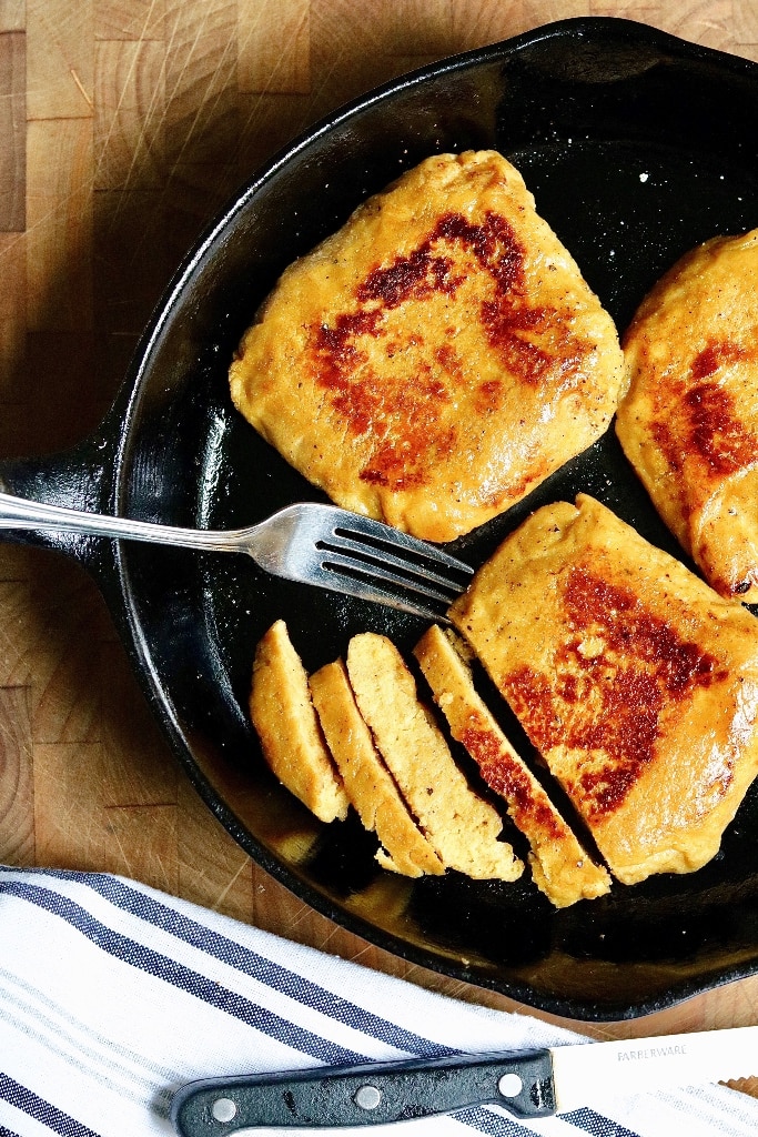 three vegan chicken breasts cooked in a frying pan partially sliced