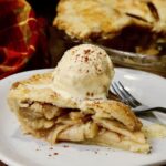 a slice of vegan apple pie with a scoop of dairy free ice cream on top