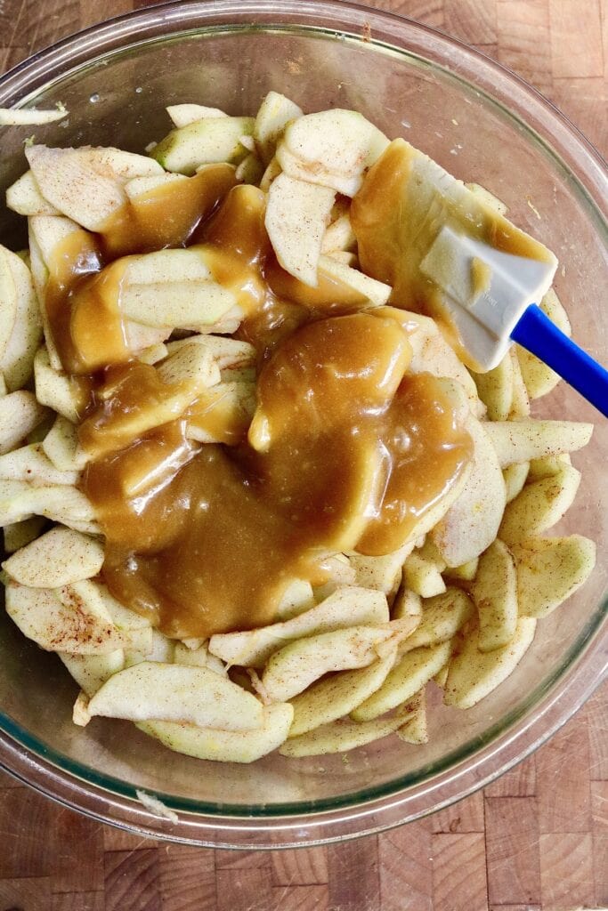 apples and caramel sauce ingredients mixed in a bowl for apple pie filling 