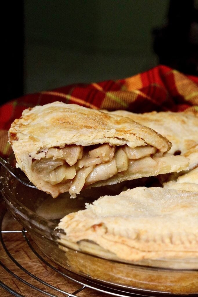 a slice of vegan apple pie being removed from pie plate 