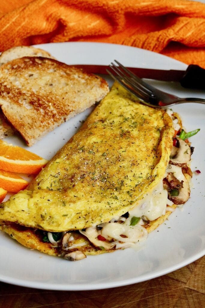 just egg omelette on a white plate with toast and orange slices ready to eat