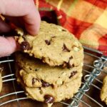 vegan pumpkin chocolate chip cookies stacked on a cooling rack