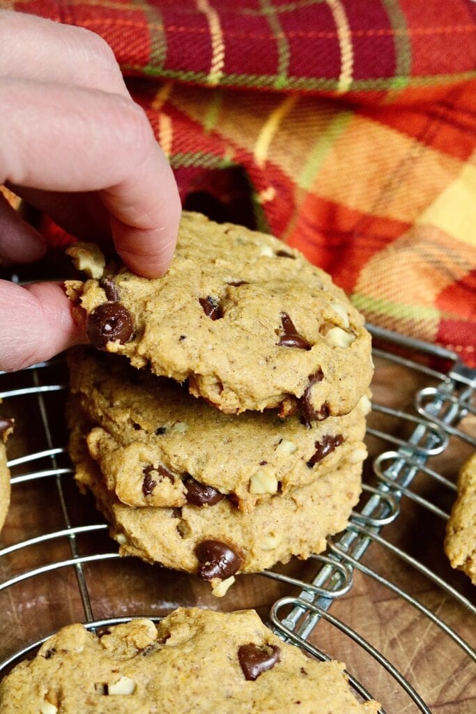 vegan pumpkin chocolate chip cookies stacked on a cooling rack