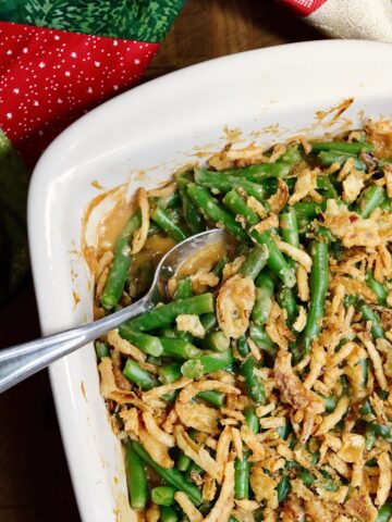 vegan green bean casserole baked in a dish with a serving spoon