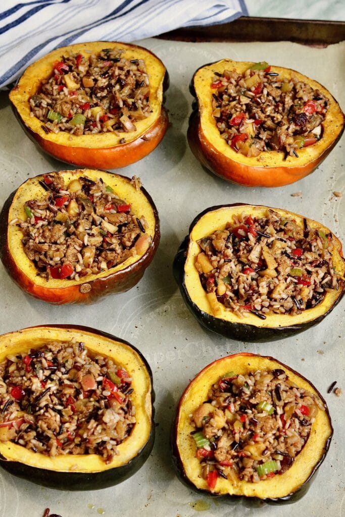 six stuffed acorn squash on a baking sheet ready to serve