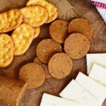 vegan pepperoni sliced on cutting board with cheese and crackers ready for pizza or charcuterie platter