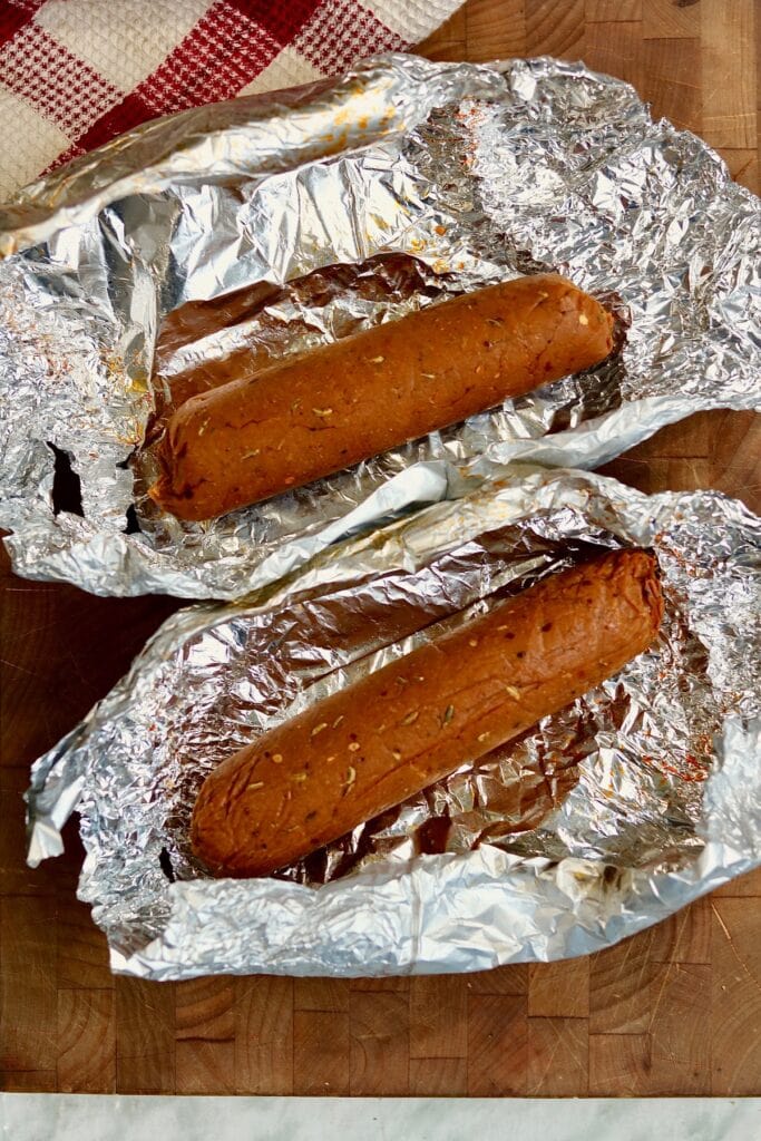 two vegan pepperoni logs unwrapped from tin foil