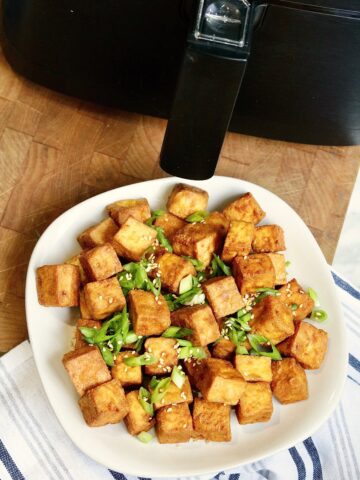 air fried tofu on a plate beside an air fryer