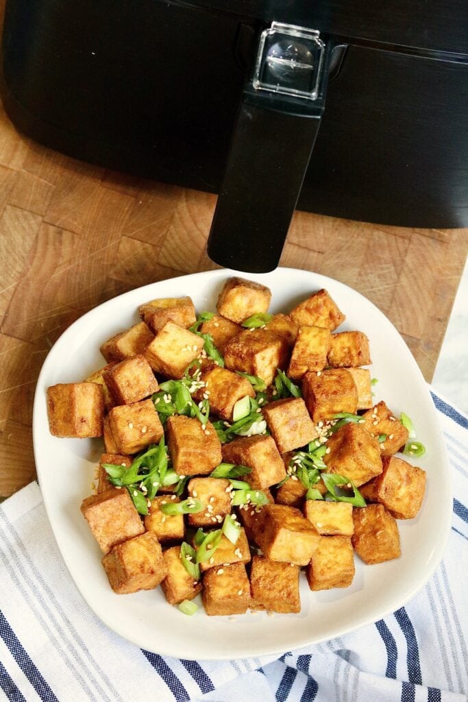 air fried tofu on a plate beside an air fryer