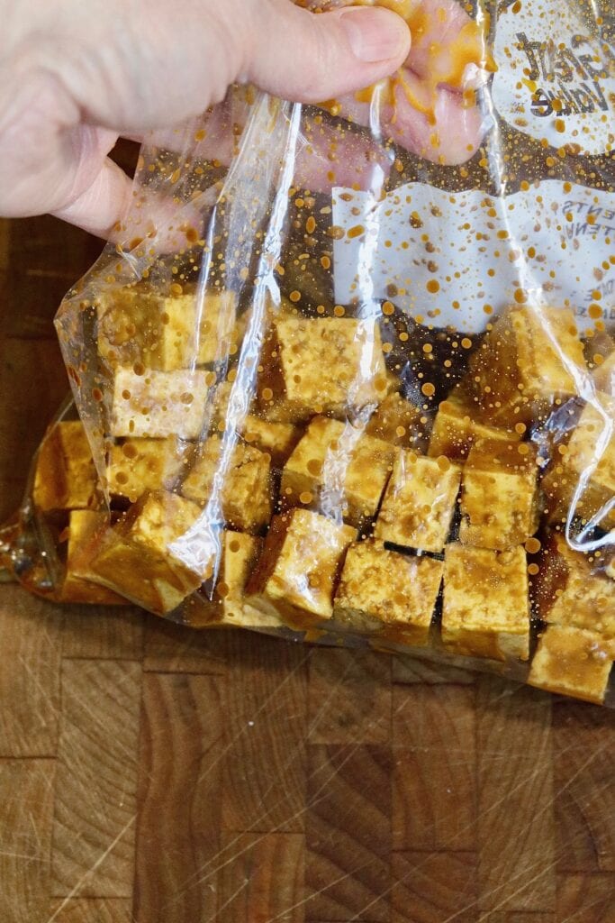 cubed tofu and marinade ingredients marinating in a ziplock bag