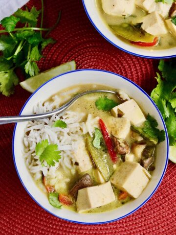a bowl of thai green curry with tofu and vegetables in a bowl with rice