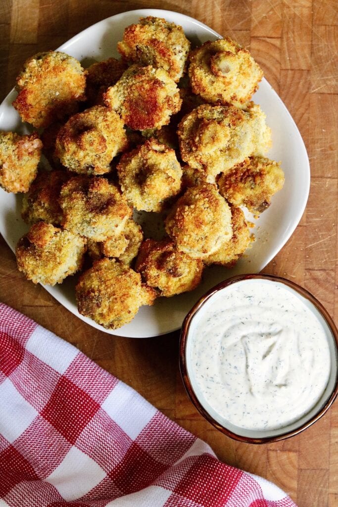 air fryer breaded mushrooms on a plate with vegan ranch dressing