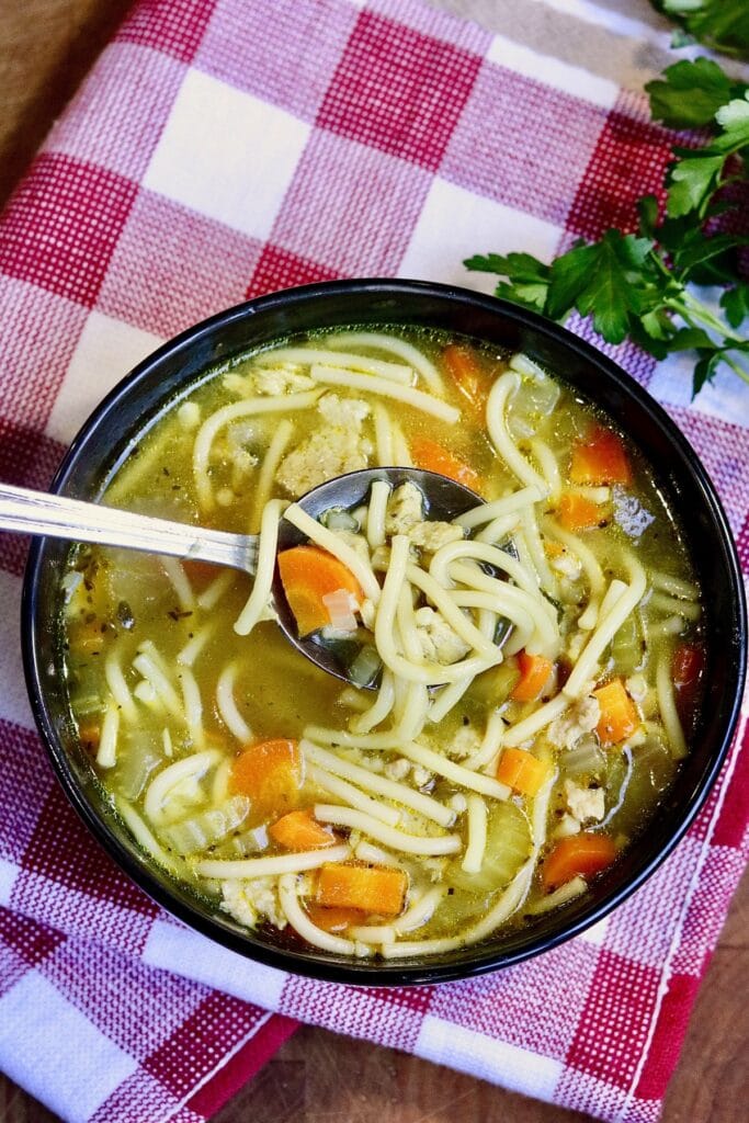 vegan chicken noodle soup in a bowl with a spoonful being lifted out