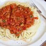 spaghetti noodles on a plate covered with vegan meat sauce