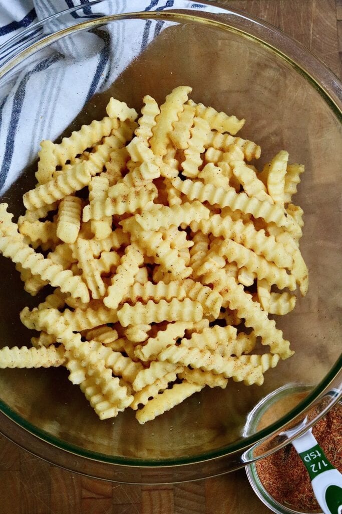 frozen french fries with oil and seasoning in a bowl