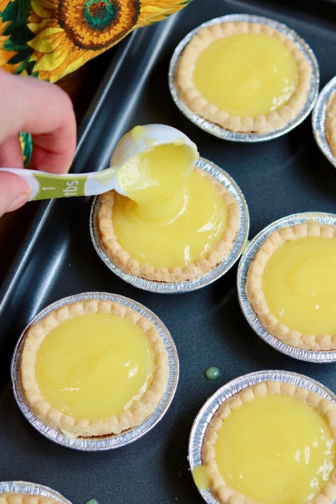 tart shells being filled with lemon curd