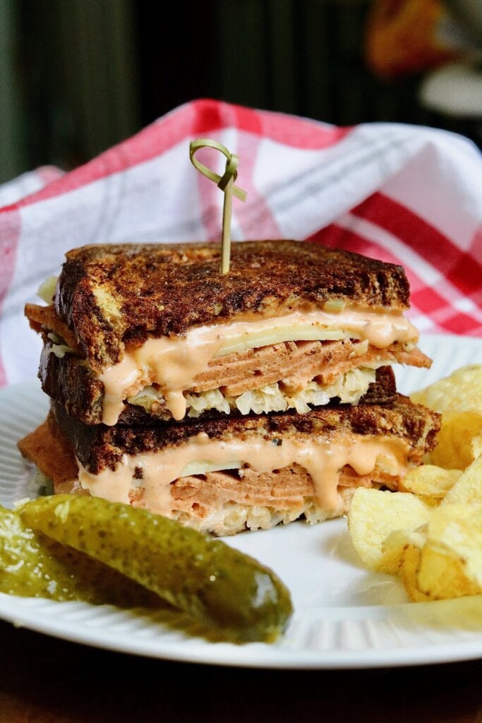 vegan reuben sandwich sliced in half on a plate