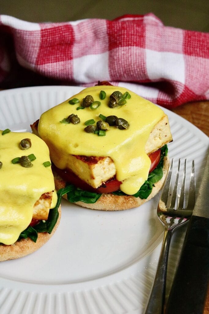 tofu eggs benedict on a plate with a fork and knife