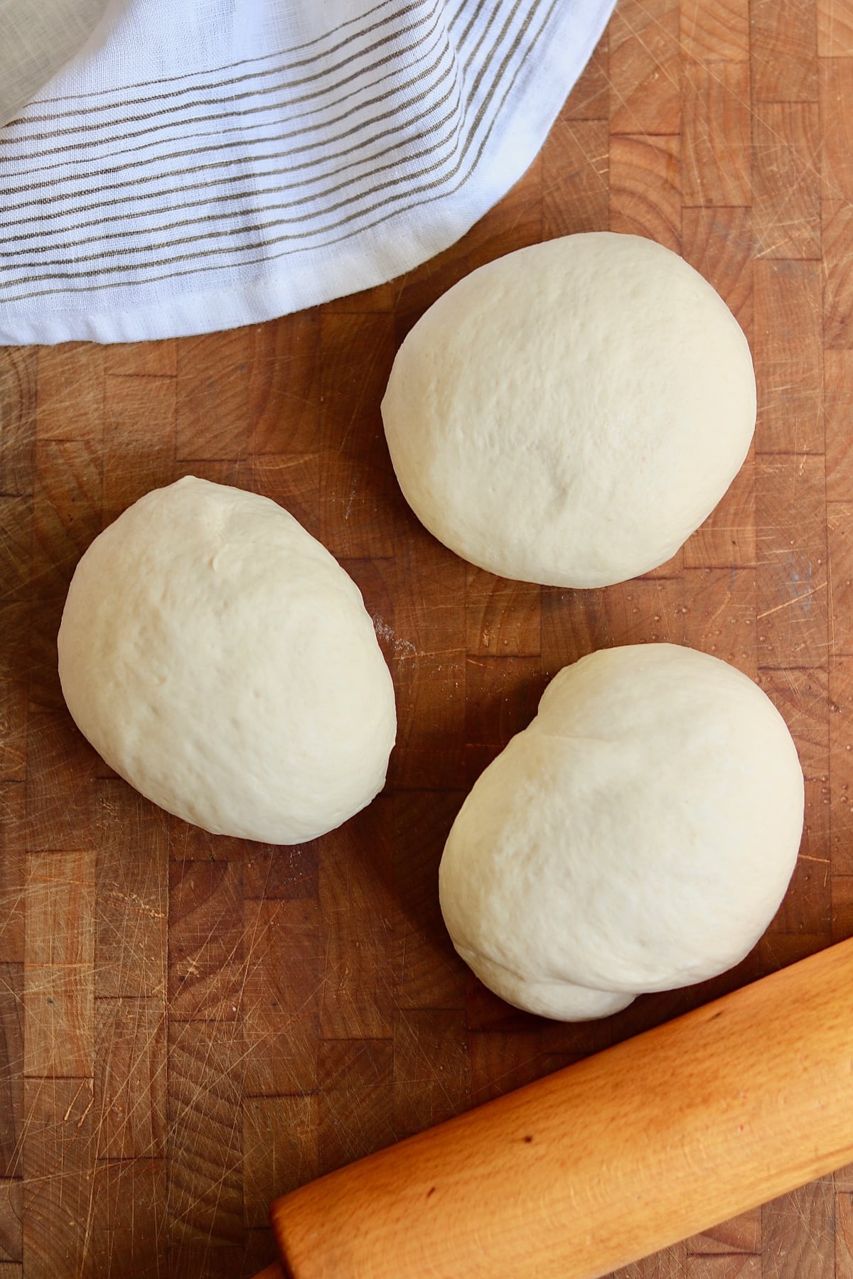 three pizza dough balls on a countertop