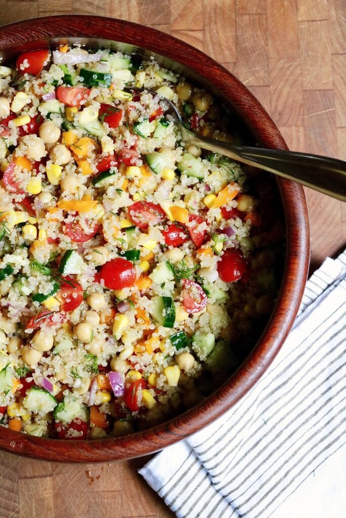 quinoa salad with chickpeas and veggies in a salad bowl with serving spoon