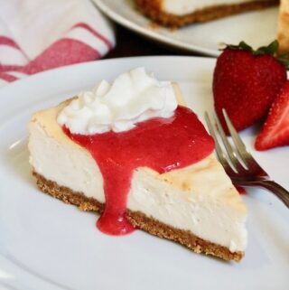 a slice of baked vegan cheesecake on a plate with strawberry sauce