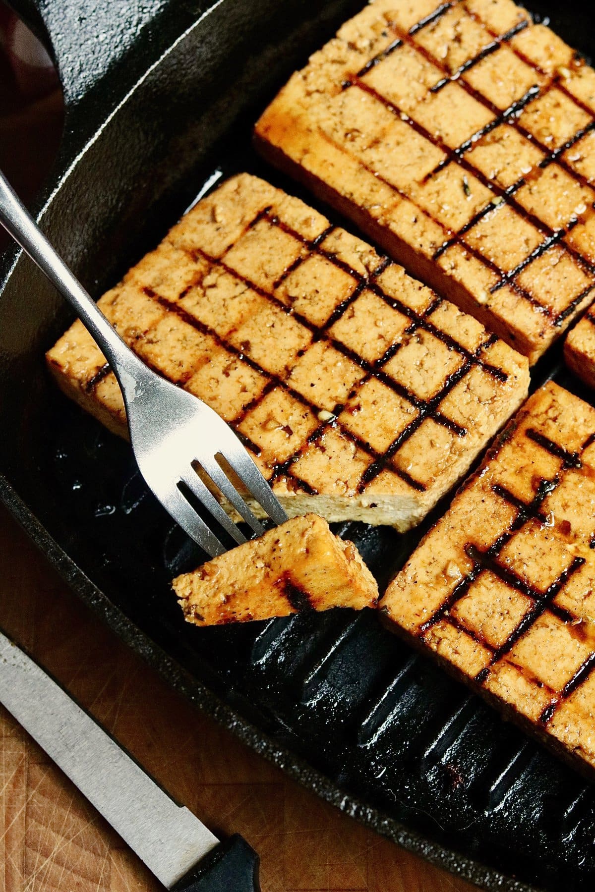 grilled tofu steak being sliced 