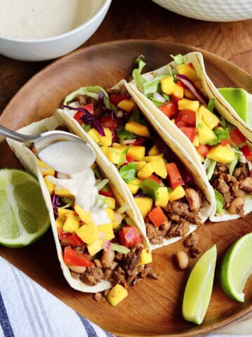 vegan jerk tacos on a plate with mango salsa and lime wedges